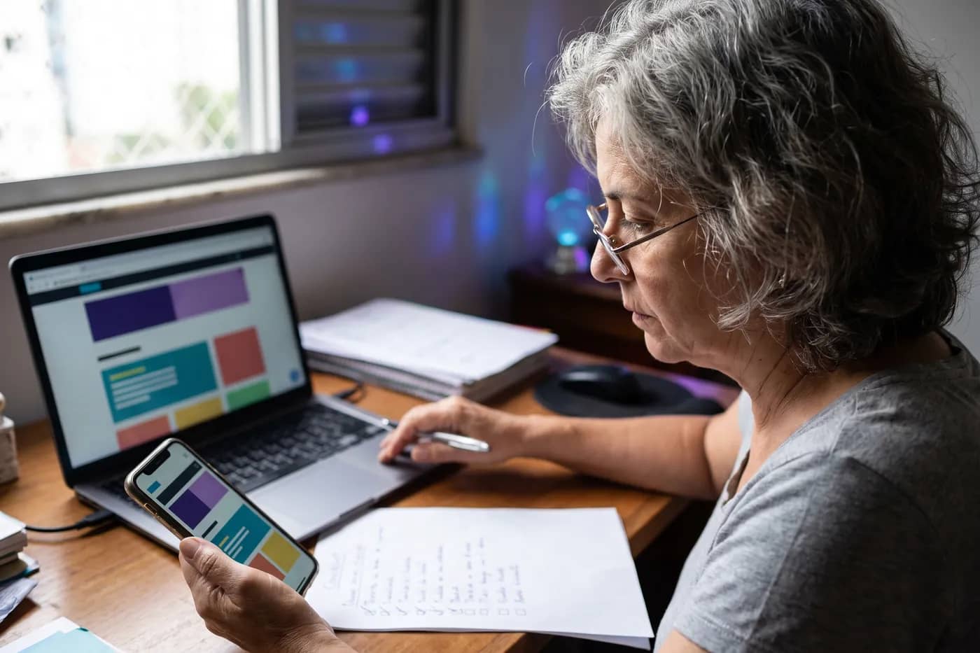 Pessoa avaliando um site no notebook e no celular ao mesmo tempo