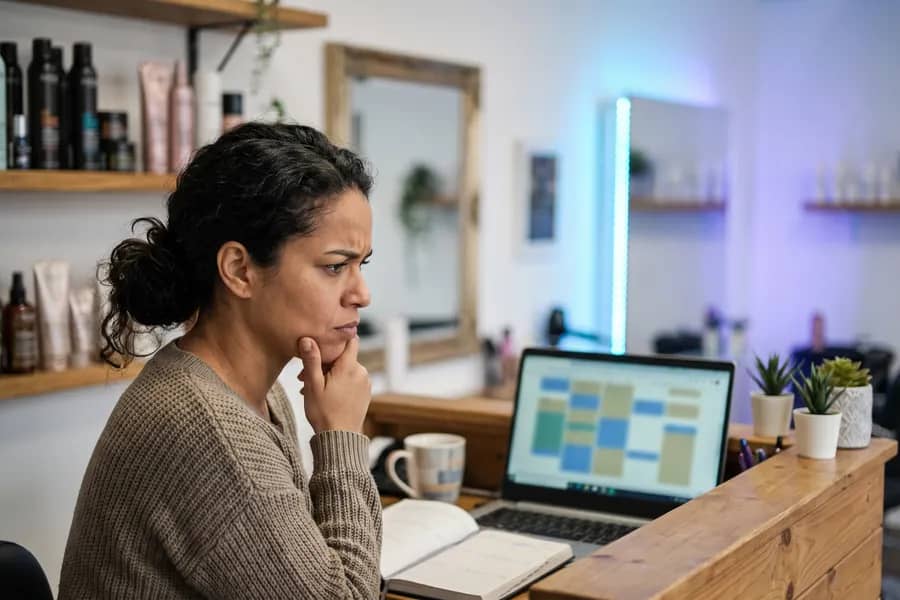 Empreendedora analisando o site da empresa no notebook com expressão pensativa