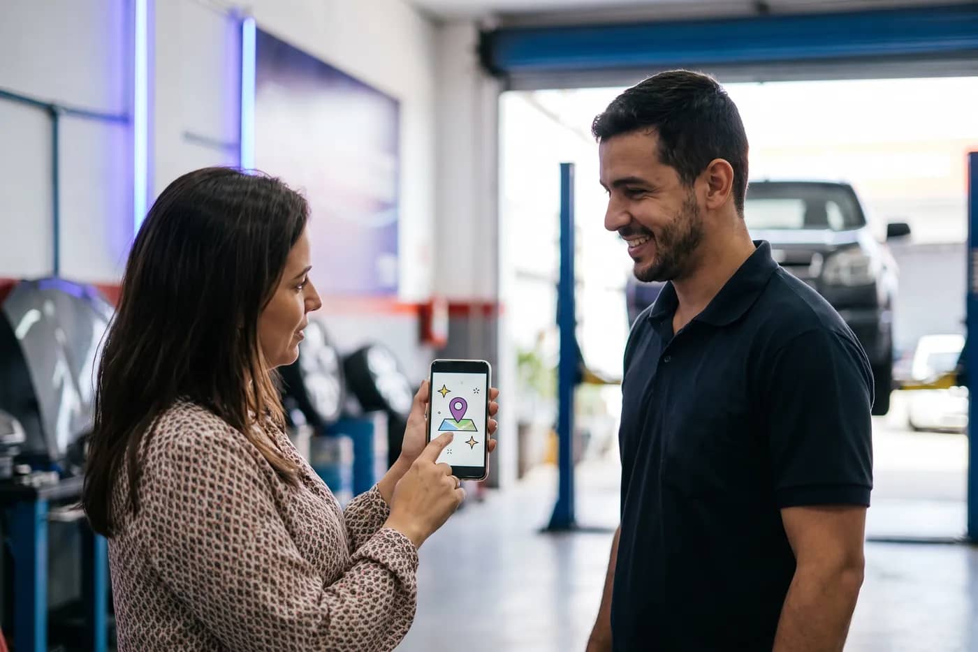 Cliente mostrando no celular o perfil de uma oficina enquanto conversa com o dono